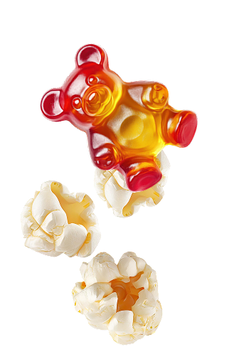 Kilka kawałków popcornu i żelka w kształcie misia na białym tle – przykłady przekąsek, które mogą mieć wpływ na użytkowanie nakładek ortodontycznych Invisalign®.