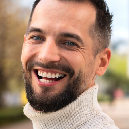 Uśmiechnięty mężczyzna, Paweł, 40 lat – przykład zdrowego uśmiechu po leczeniu ortodontycznym z użyciem nakładek Invisalign®.