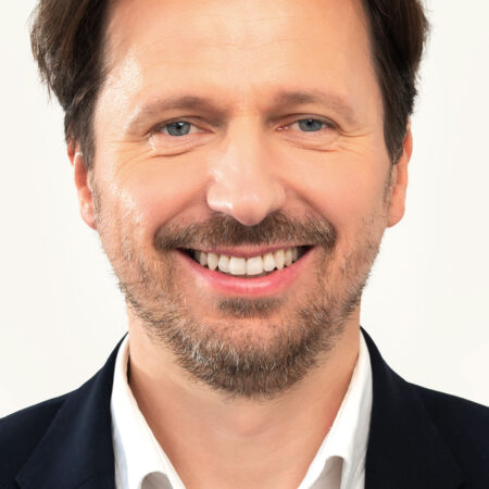 Uśmiechnięty mężczyzna, Bartosz, 46 lat – przykład zdrowego uśmiechu po leczeniu ortodontycznym z użyciem nakładek Invisalign®.