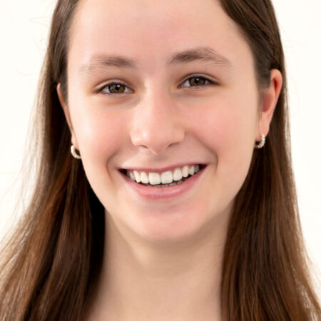 Uśmiechnięta nastolatka z długimi włosami, obok panoramiczne zdjęcie rentgenowskie zębów – przykład diagnostyki ortodontycznej i leczenia nakładkami Invisalign® u młodzieży.