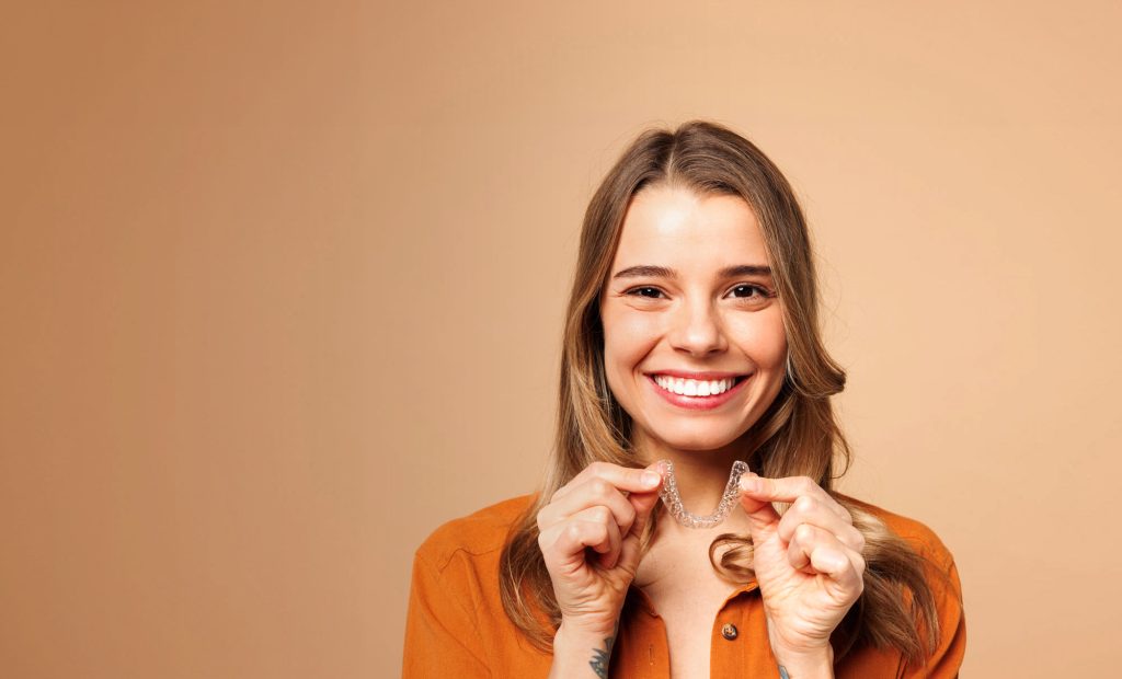 Młoda kobieta z nakładką Invisalign w dłoni