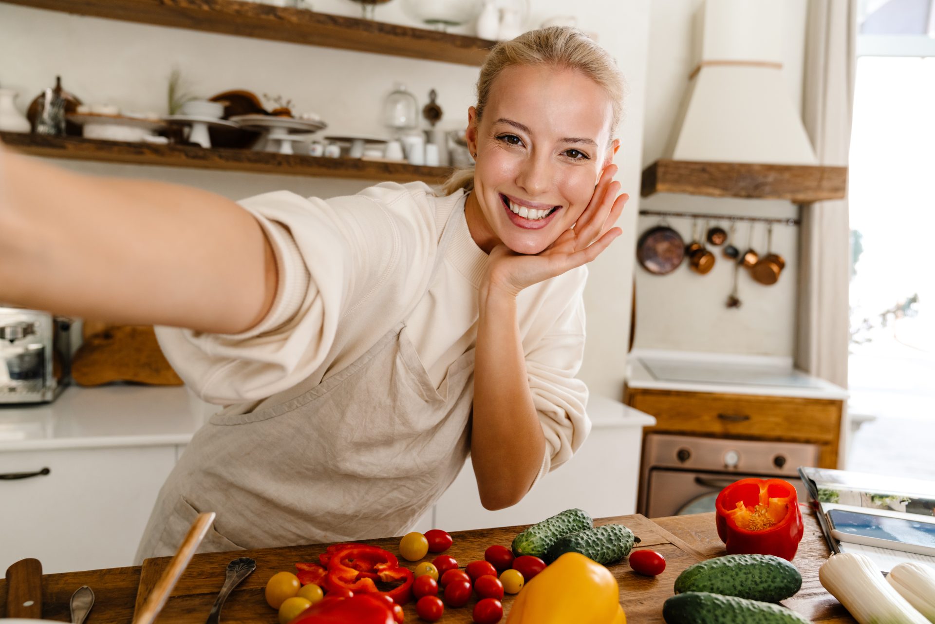 Uśmiechnięta kobieta przygotowująca posiłek w kuchni.