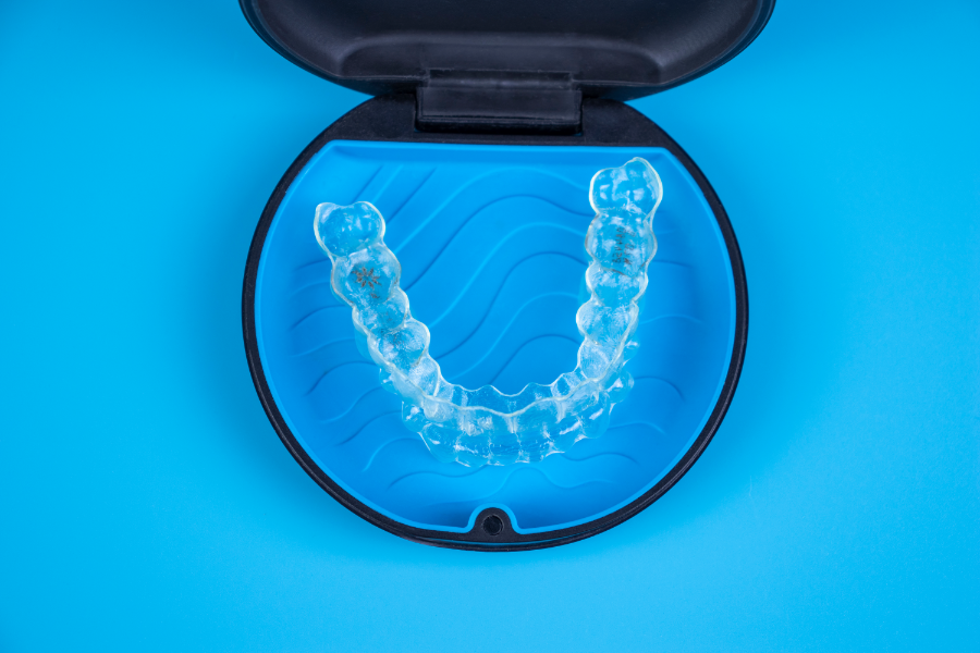 Nakładki Invisalign w niebieskim pudełku do przechowywania.