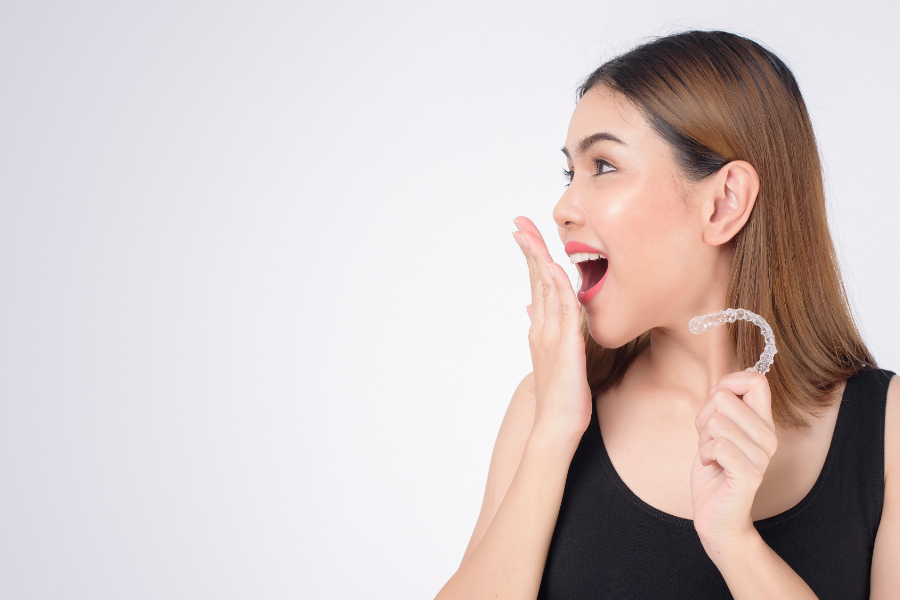 Zaskoczona kobieta trzymająca w ręce nakładkę Invisalign