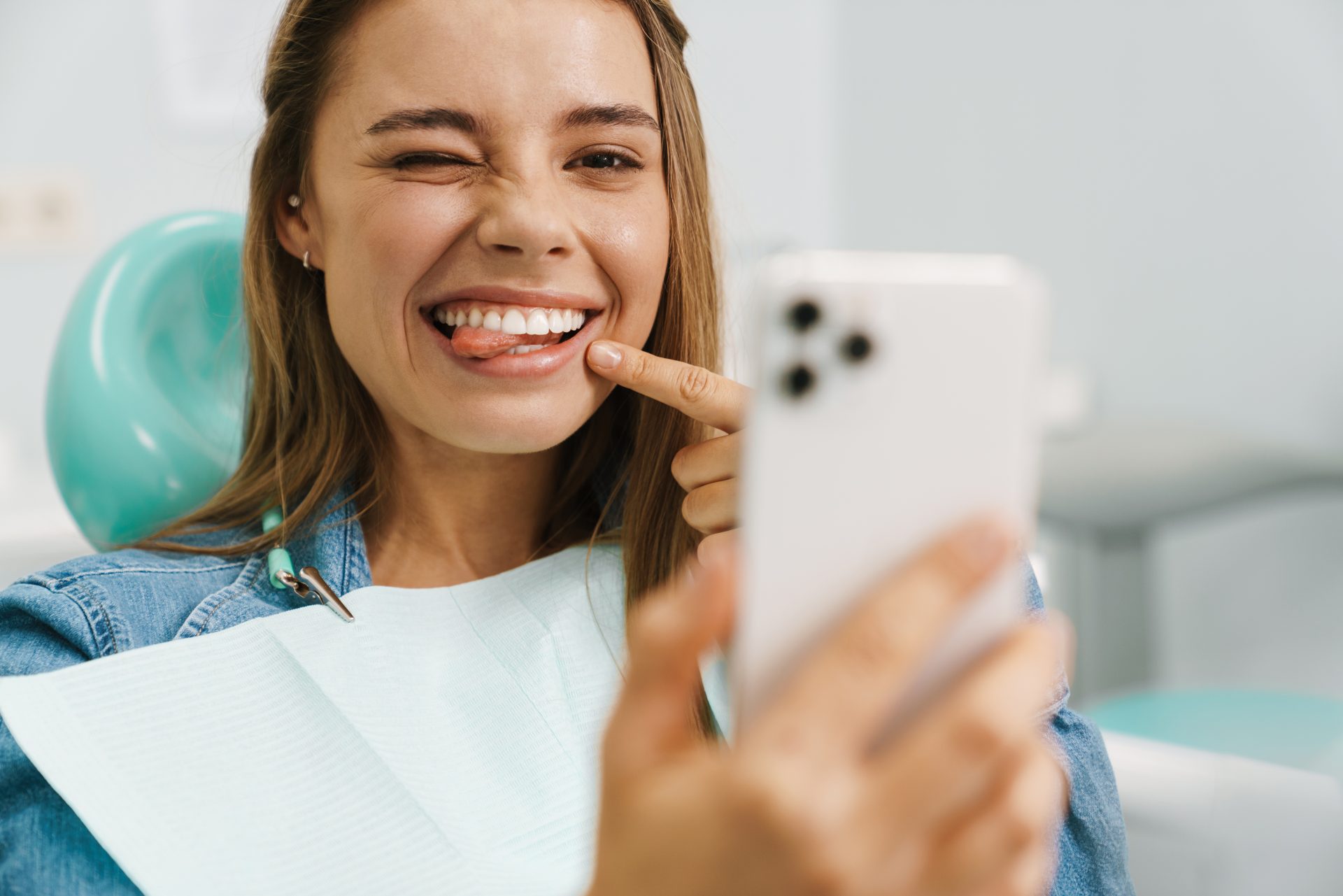 Młoda kobieta na fotelu stomatologicznym robiąca selfie.