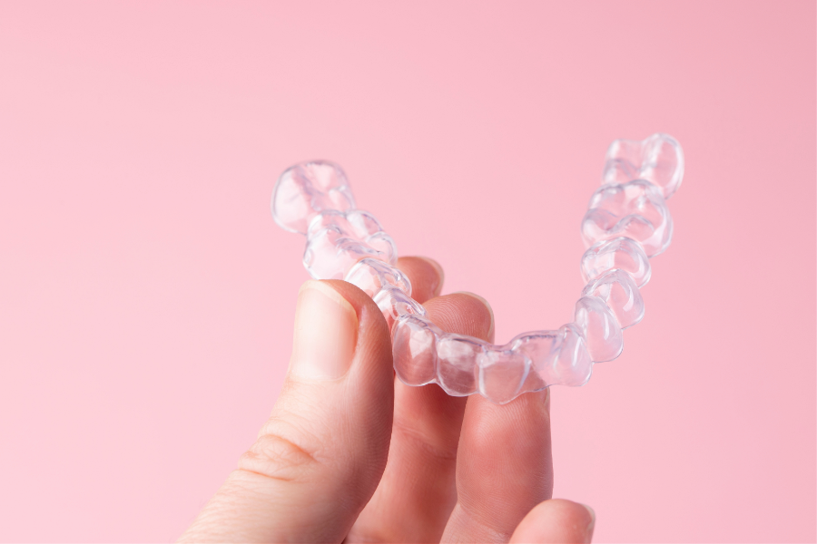 Dłoń trzymająca przezroczystą nakładkę ortodontyczną